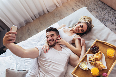 Young happy couple having breakfast in luxury hotel room.