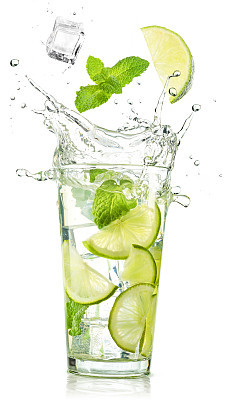 lime and mint falling into a mojito glass splashing