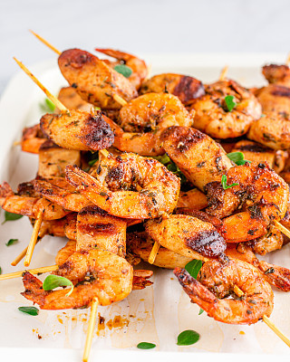 Grilled Shrimp on Skewers Served with Lemon and Oregano on a Baking Sheet