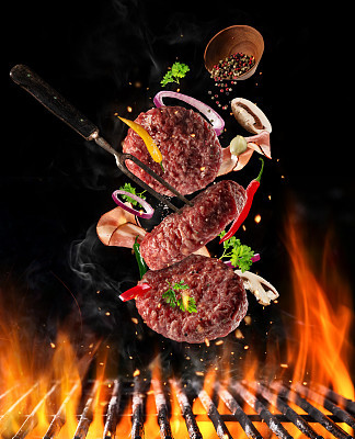 Flying raw milled beef meat with ingredients above grill fire