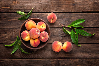Fresh juicy peaches with leaves on dark wooden rustic background