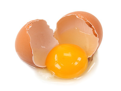 Egg shell broken in middle with yolk and white spilling out