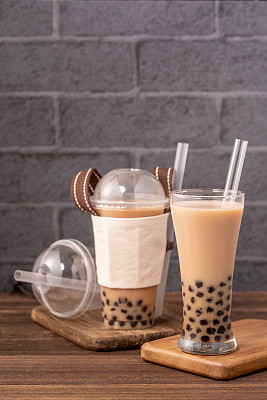 Takeout with disposable item concept popular Taiwan drink bubble milk tea with plastic cup and straw on wooden table background, close up, copy space