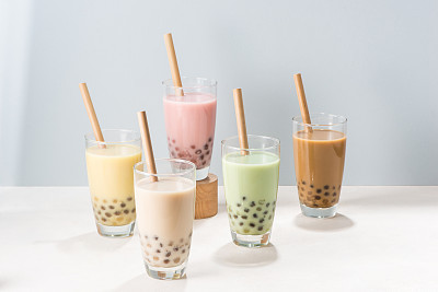 Five glasses of healthy milky boba or bubble tea flavored with fresh fruit and chocolate and served with traditional wide straws
