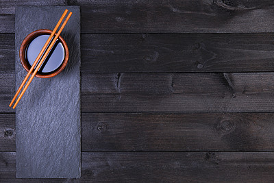 Background for sushi. Soy sauce, chopsticks on black table. Top view with copy space