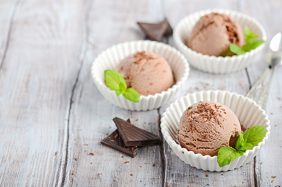 Chocolate ice cream in a white bowls on a wooden table.