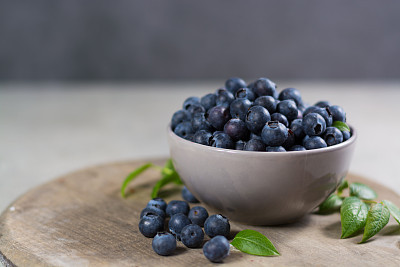 Freshly picked juicy blueberries with green leaves on rustic table. Bilberry on wooden Background. Blueberry antioxidant. Concept for healthy eating and nutrition