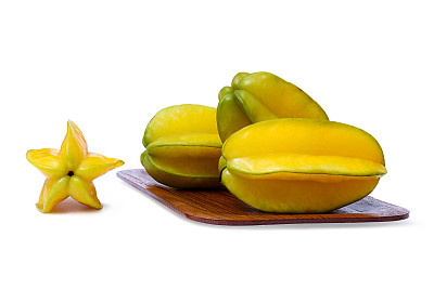 Yellowish green star fruit on the wooden rounded rectangle tray isolated on white background