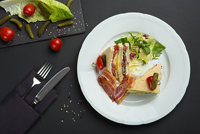Sandwich with bacon and vegetables on black background. breakfast or lunch dish.
