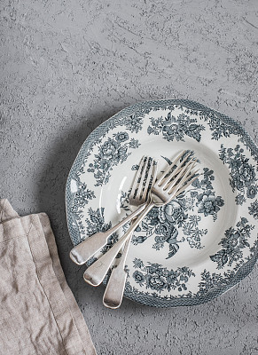 Vintage style plate and forks on a grey table, top view