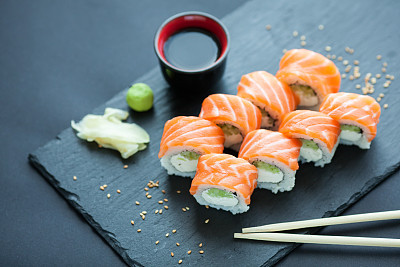 Philadelphia roll classic dark stone on the Board. Salmon, Philadelphia cheese, cucumber, avocado. Japanese sushi.