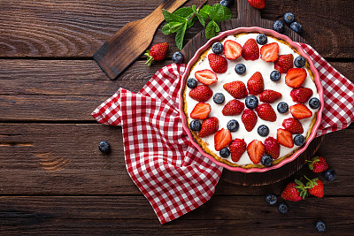 Delicious strawberry pie with fresh blueberry and whipped cream on wooden rustic table, cheesecake, top view