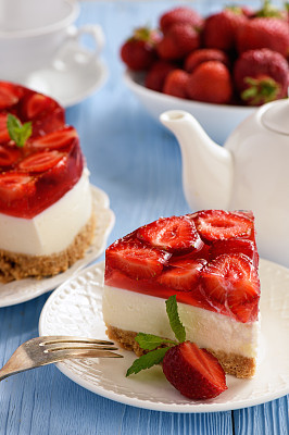 Homemade strawberry cheesecake on blue wooden background.