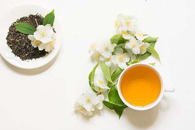 Jasmine dry green tea leaves with fresh jasmine flowers and cup of tea on white background.