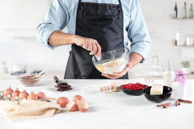 A cook with eggs on a rustic kitchen against the background of men's hands