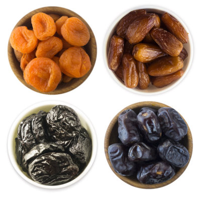 Collage of different dried fruits. Dried prunes, dried apricots and dates isolated on white background. Top view. Dried fruits isolated on a white background. Dried fruits in a bowl on white background. Dried fruits with copy space for text.