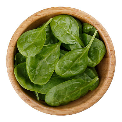 Fresh baby spinach leaves in wooden bowl isolated on white background. Top view