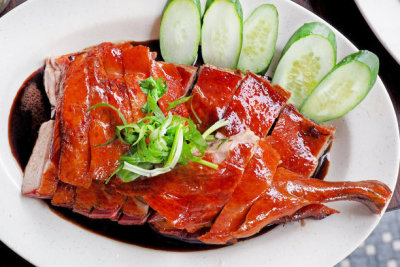 Chinese Roasted duck cutted and served on white dish topped with black gravy herbal sauce viewed from top