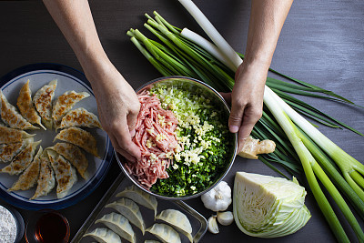 Japanese style dumplings. Taken from above, dumpling recipes and ingredients to make dumplings and baked dumplings. Senior woman's hands mix the ingredients.