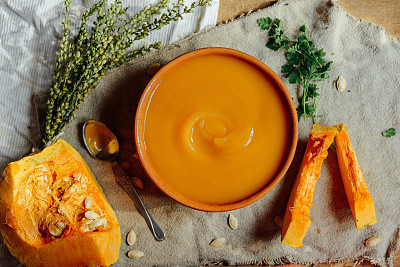 Pumpkin porridge and pumpkins on black wooden table. Plate pumpk