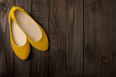 Yellow women's shoes (ballerinas) on wooden background.