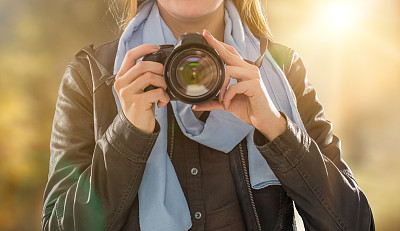 Portrait of a photographer covering her face with camera.