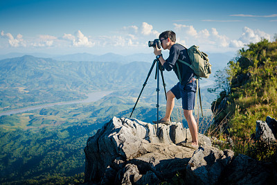 Young traveler standing on the mountains looks into the sunset.