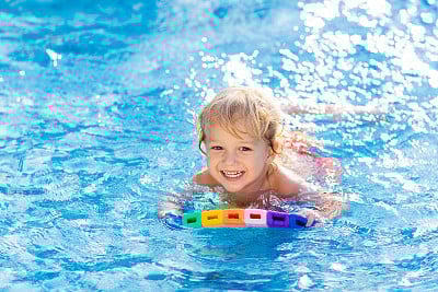 Child learning to swim. Kids in swimming pool.