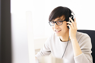 Young Professional Man Wearing Headphones Concentrating on Computer Screen