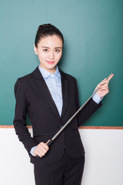 portrait of female teacher holding pointer stick front of blackboard