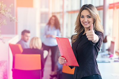 portrait of young business woman at modern startup office interior showing thumbs up