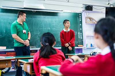 Teacher looking at schoolboy against blackboard