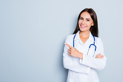 Smiling happy doctor pointing with finger on blue background