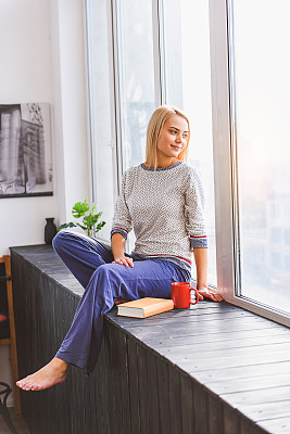 Dreamful woman enjoying view on windowsill