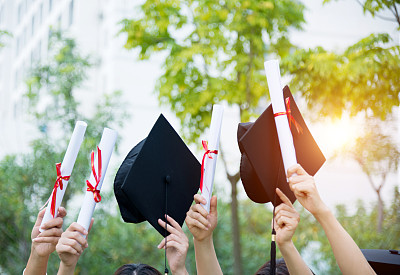Graduates holding motarboards and diplomas