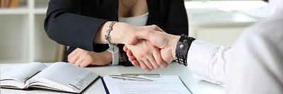 Businessman and woman shake hands as hello in office