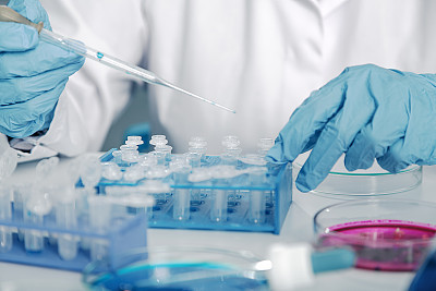 Pipette adding fluid to one of several test tubes .medical glassware