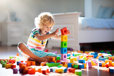 Child playing with colorful toy blocks. Kids play.