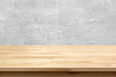 Wood table top on bare concrete wall background