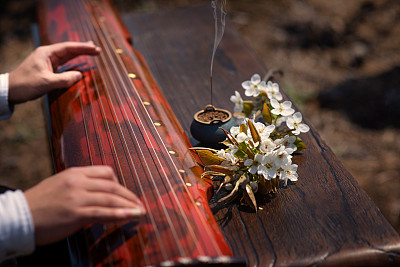 The man is playing the Guqin