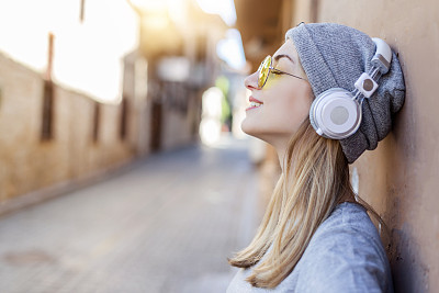 Young woman listen music close to wall