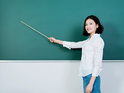 Young female teacher pointing to chalkboard