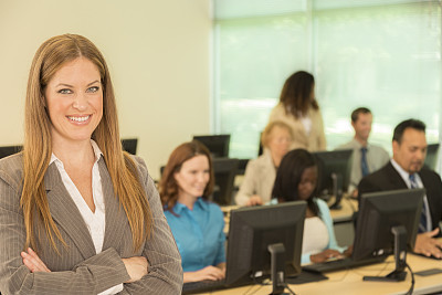 Education: Female college instructor with computer lab students.
