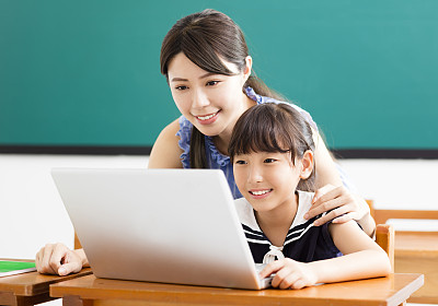 young Teacher helping child with computer lesson