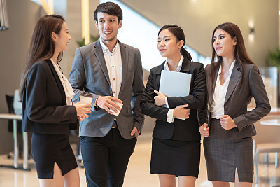 Asian business people discussion in office building. Young businessman and businesswoman colleague talk to each other during the break.