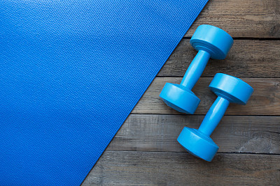dumbbells and yoga mat on wood table