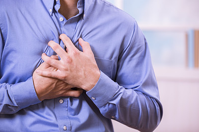 Healthcare: Man clutching his chest in pain, possible heart attack.