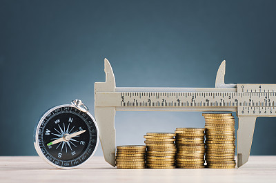 saving money concept,vernier caliper and stacking coins on wooden desk over beautiful reverberation gradient background