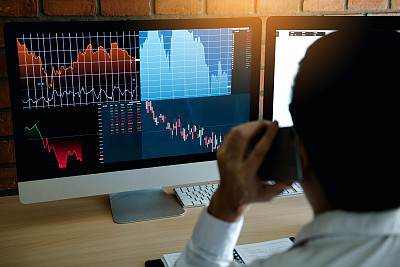 Agent trader man talking at telephone and checking business stock data on computer in office room.