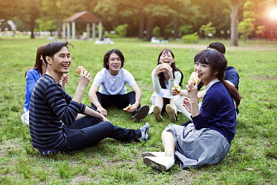 Happy group of Japanese friends eat in the park, Tokyo